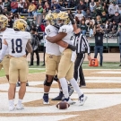 UCD football players celebrating touchdown in the end zone