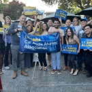 Mix of 15 people holding UCD signage