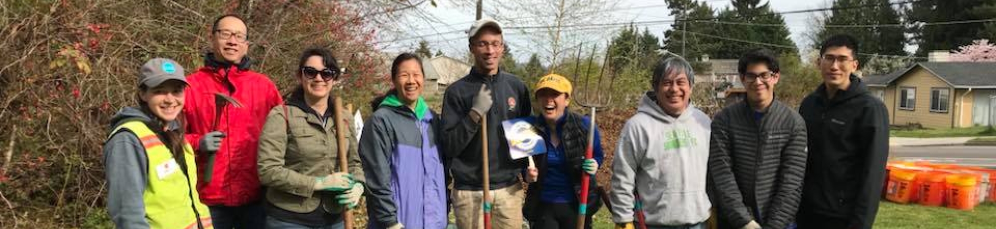 A group of UC Davis alumni in Seattle at a community service day posing with shovels outdoors