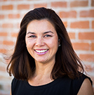 Heidi Jannenga smiling at camera in front of brick wall